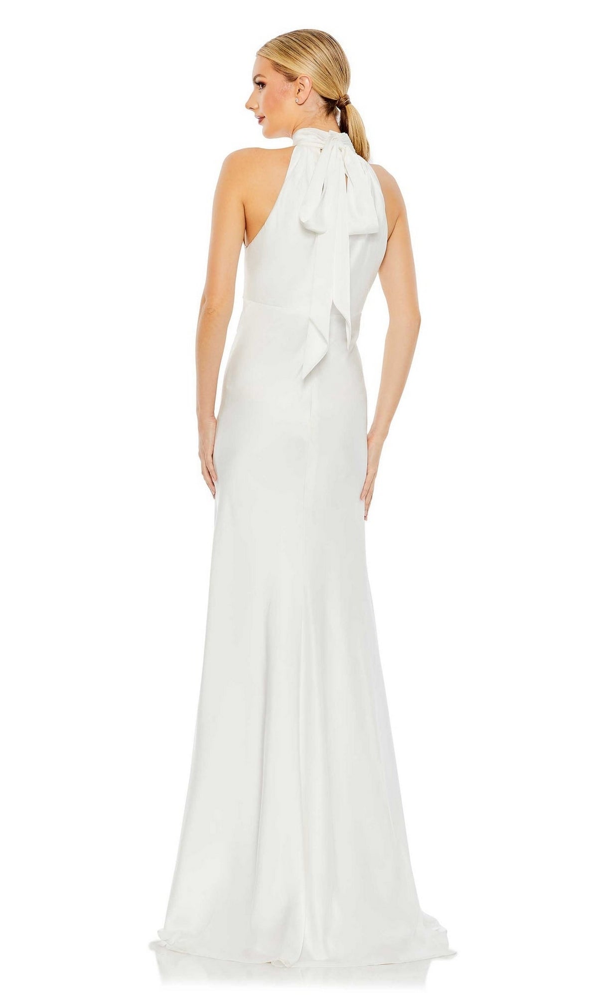 A woman stands facing away from the camera, wearing the Long Formal Dress 49520 by Mac Duggal—a sleeveless, floor-length white gown featuring a high neck with bow detail.